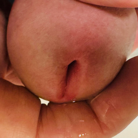 Nahaufnahme eines Penis. Eine Hand umfasst die errigierte Eichel. Lusttropfen fließen über den Zeigefinger.